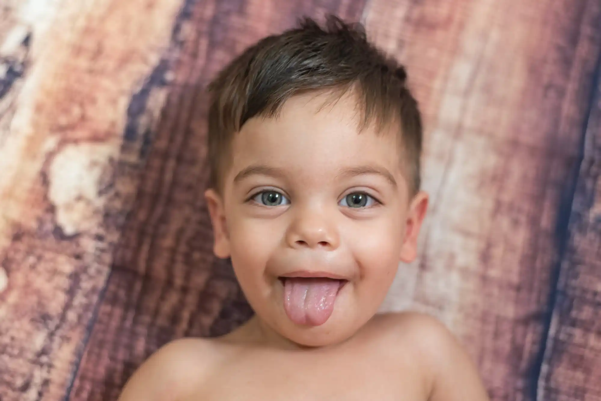 bambino con occhi azzurri e lingua fuori